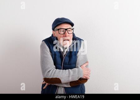 Senior uomo in maglione, giubbotto giacca e cappuccio, studio shot. Foto Stock