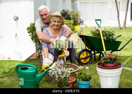 Ritratto di coppia senior che abbraccia ogni altra in cortile Foto Stock