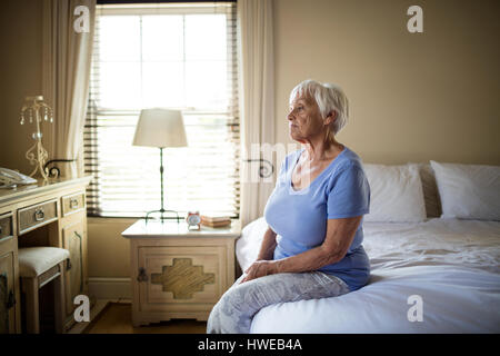 Preoccupato senior donna seduta sul letto nella camera a casa Foto Stock