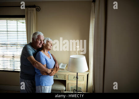 Coppia senior che abbraccia ogni altro nella camera da letto di casa Foto Stock