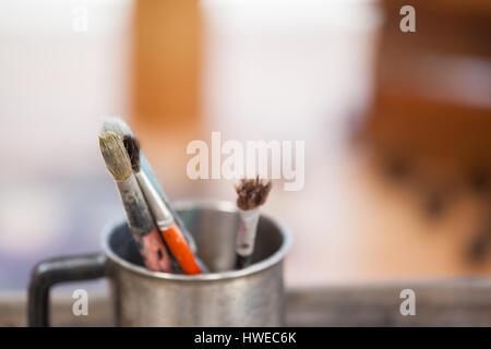 Set di pennelli per dipingere in una tazza sul tavolo di legno Foto Stock