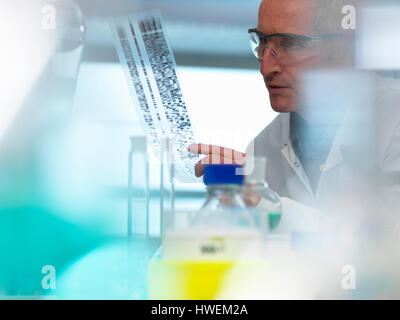 Ricercatore tenendo un DNA (acido desossiribonucleico) gel durante un esperimento genetico in un laboratorio Foto Stock