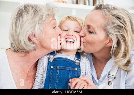 Ritratto di ragazza baciato sulla guancia dalla madre e nonna in cucina Foto Stock
