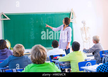 Docente alla parte anteriore della classe, spiegando la matematica problema sulla lavagna Foto Stock