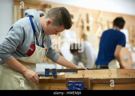 Un adolescente di sesso maschile di falegnameria di regolazione dello studente morsetto di legno nel collegio di officina Foto Stock