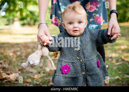 Ritratto di bambina azienda madre con le mani in mano e toddling in posizione di parcheggio Foto Stock