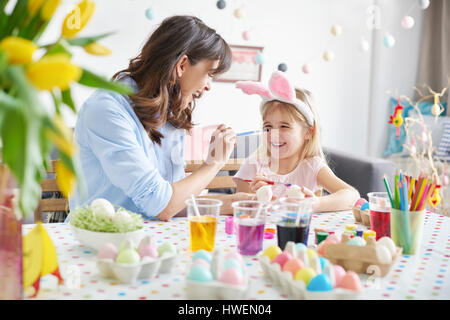 Pittura donna figlia del naso mentre la pittura delle uova pasquali a tavola Foto Stock