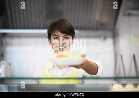 Giovane donna di consegnare il cibo al cliente in un fast food shop Foto Stock