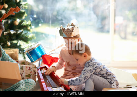 La ragazza e il fratello di vita sul pavimento in camera guardando la chitarra giocattolo regalo di natale Foto Stock