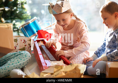 La ragazza e il fratello sul soggiorno piano guardando a chitarra giocattolo regalo di natale Foto Stock