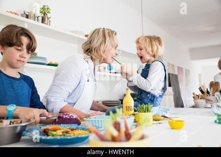 Ragazza madre di alimentazione gli asparagi al tavolo della cucina Foto Stock