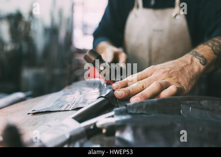 Mani di metallurgo martellamento piombo metallico fucina in officina Foto Stock