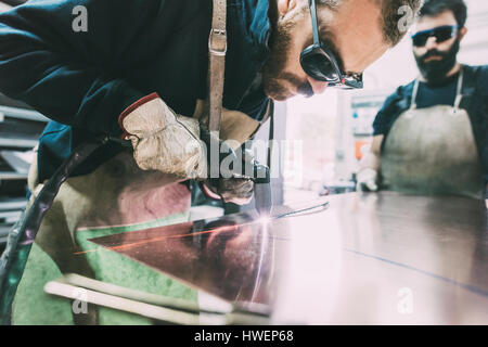 Metallurgo taglio foglio di rame con la torcia di saldatura in forge workshop Foto Stock