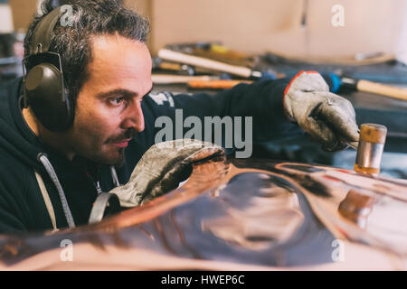 Metallurgo martellare il rame in forge workshop Foto Stock