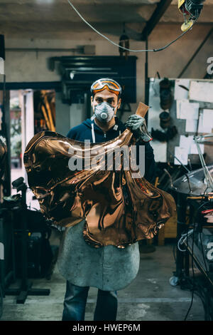 Ritratto di metallurgo azienda prodotto in rame in forge workshop Foto Stock