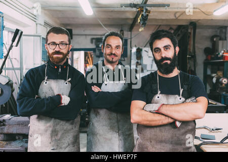 Ritratto di tre dei metalmeccanici maschio in forge workshop Foto Stock