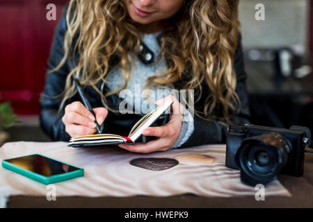 Donna al cafe iscritto nel notebook Foto Stock