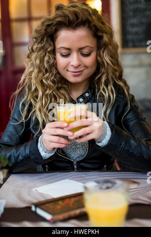 Donna al cafe di bere succo di arancia Foto Stock