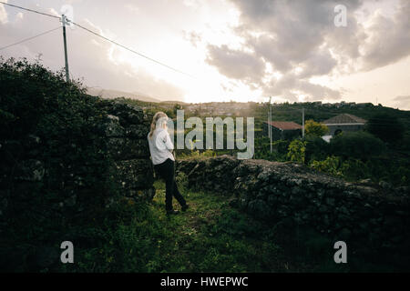 Donna che guarda fuori oltre il paesaggio di vigneti Foto Stock