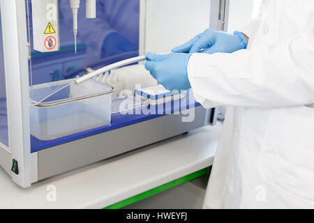 Scienziato in laboratorio lavora con automatico sistema di pipettaggio. Manipolazione di liquidi robot. Foto Stock