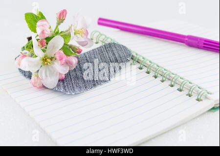 Cuore denim sul notebook aperto con molla sbocciare fiori Foto Stock