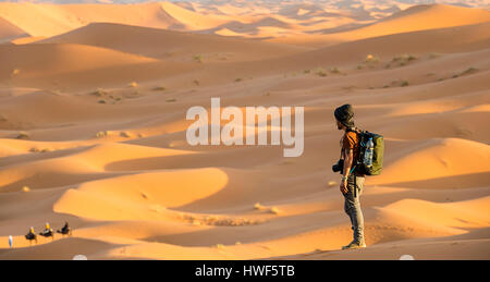 Un uomo si gode della vista dalla cima del deserto del Sahara dune al tramonto - Merzouga - Marocco Foto Stock