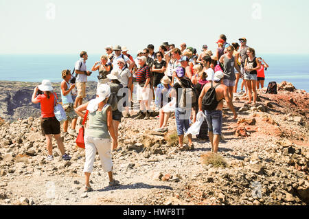 Un gruppo di tour si radunano in cima ad una collina sulla centrale del vulcano di Santorini nelle isole greche. Foto Stock