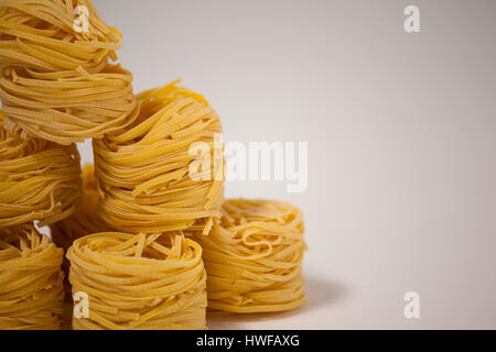 Tagliatelle disposti in una fila su sfondo bianco Foto Stock