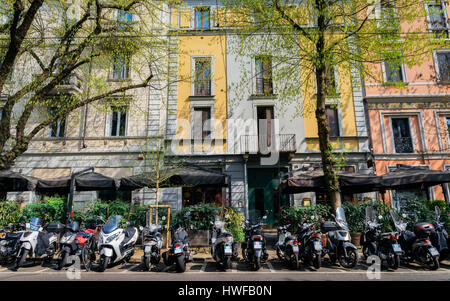 Vespa italiana su un interno occupato e colorata Milano street con caffè e ristoranti Foto Stock