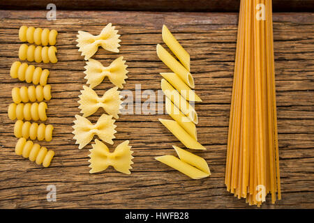 Varie pasta disposte in fila su una superficie di legno Foto Stock