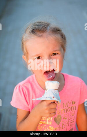 La ragazza di t-shirt rosa lecca il gelato Foto Stock