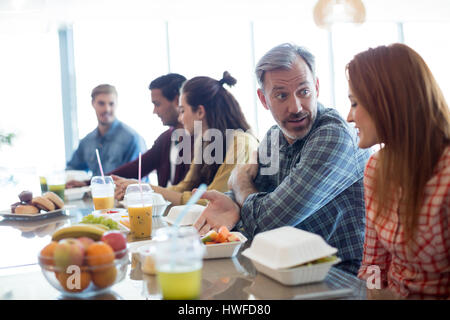 Creative team business discutendo pur avendo pranzo in ufficio Foto Stock