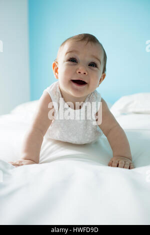 Carino sorridente bambina sul letto in camera da letto Foto Stock