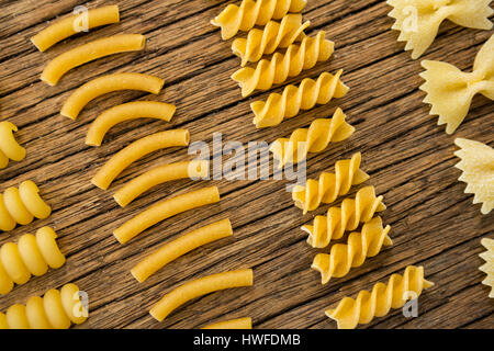 Varie pasta disposte in fila su una superficie di legno Foto Stock