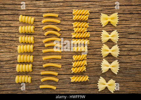 Varie pasta disposte in fila su una superficie di legno Foto Stock
