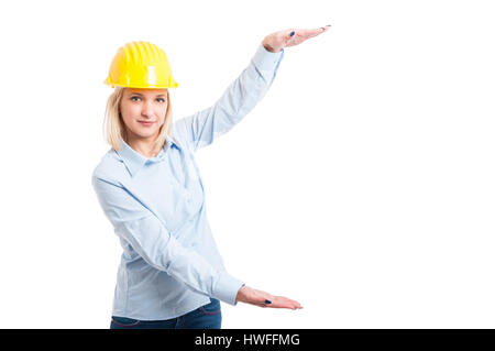 Signora engineer indossando il casco che mostra o in possesso di copia di grande spazio isolato su sfondo bianco con Copia area di testo Foto Stock