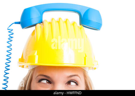 Close-up di donna ingegnere occhi guardando trasversalmente con telefono del ricevitore sulla parte superiore del cappello isolati su sfondo bianco Foto Stock