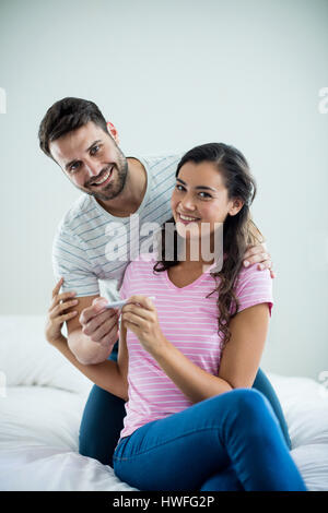 Gioiosa giovane trovare i risultati di un test di gravidanza in camera da letto a casa Foto Stock