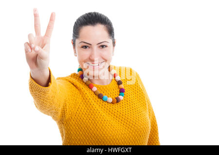 Bella donna facendo un gesto di vittoria e sorridente su sfondo bianco con copytext Foto Stock