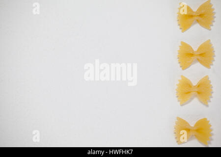 Farfalle di pasta disposte in una fila su sfondo bianco Foto Stock