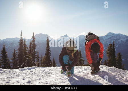 Due sciatore la legatura i loro lacci delle scarpe su strade coperte di neve montagna durante l inverno Foto Stock