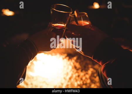 Tagliate le mani del giovane azienda bevande contro la masterizzazione di una buca per il fuoco di notte durante il periodo invernale Foto Stock