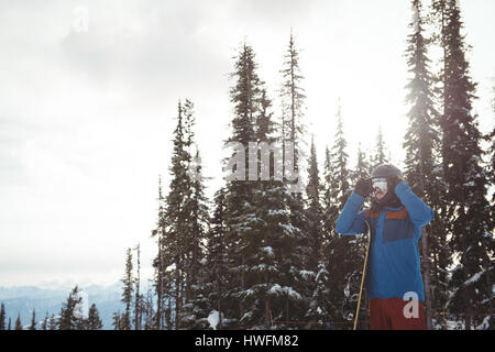 Uomo che indossa il casco contro alberi durante il periodo invernale Foto Stock