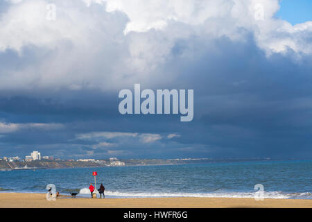 Poole, Dorset, Regno Unito. Il 20 marzo 2017. Regno Unito: meteo visitatori godere del sole serale con cielo tempestoso overhead a cui Canford Cliffs e Branksome spiagge. Dog walker e guida presso la riva del mare godendo il sole con minaccioso sopra le nuvole. Credito: Carolyn Jenkins/Alamy Live News Foto Stock