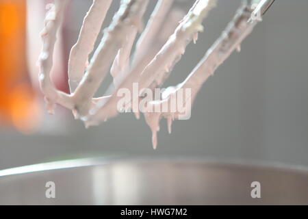 In prossimità di una frusta ricoperto di glassa mentre la cottura a casa pan di spagna per un compleanno. Foto Stock