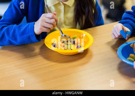 I bambini della scuola elementare di preparare una insalata di frutta in una scuola inglese Foto Stock