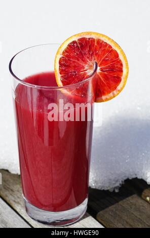 Un bicchiere di fresco rosso rubino sangue succo di arancio con un sangue fetta di arancia in inverno Foto Stock