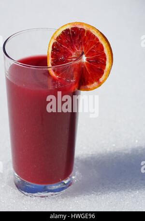 Un bicchiere di fresco rosso rubino sangue succo di arancio con un sangue fetta di arancia in inverno Foto Stock