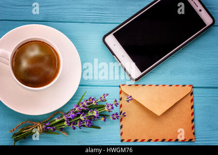 Vuoto notebook bianco, Busta, telefono,mazzetto di lavanda e tazza di caffè sulla scrivania Foto Stock