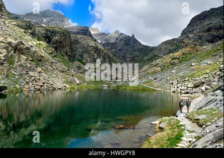 Francia, Alpes Maritimes, Parc national du Mercantour (Parco Nazionale del Mercantour), la Vallee des Merveilles (Valle delle Meraviglie) sparse con migliaia di incisioni rupestri risalenti all'età del bronzo, escursionisti sul sentiero GR 52 presso il lago di Merveilles sotto la Baisse (pass) de Valmasque e il Mont grand capelet (2915 m) sullo sfondo a sinistra Foto Stock